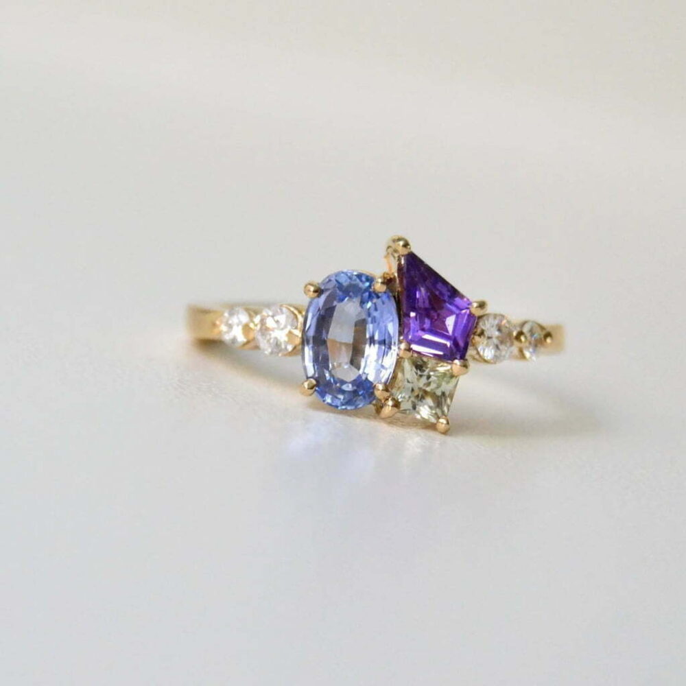 Oval blue sapphire cluster ring set with diamonds in 18K yellow gold