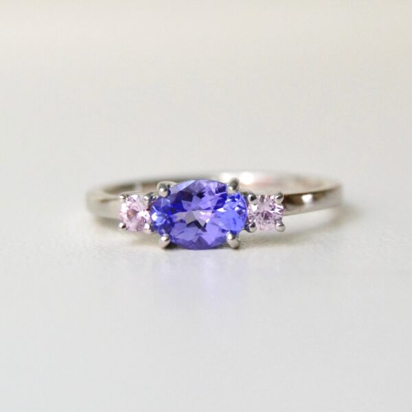 Tanzanite ring with baby pink sapphires set in a three stone design of 18K white gold