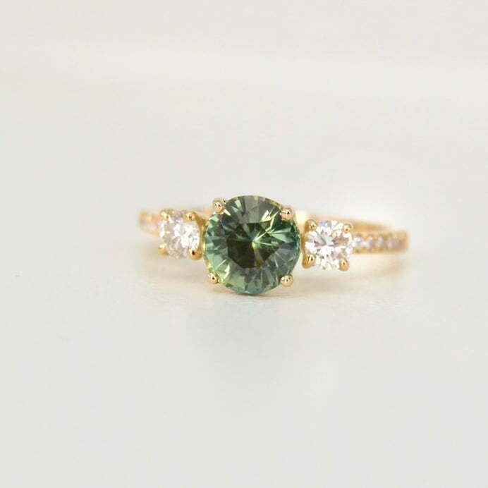 Green sapphire ring in a three stone ring design with diamonds