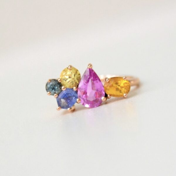 Pink sapphire ring with orange, yellow, green and teal sapphires in rose gold