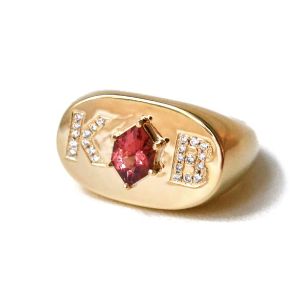 Signet ring with initials in diamonds and set with a center garnet in 14k yellow gold