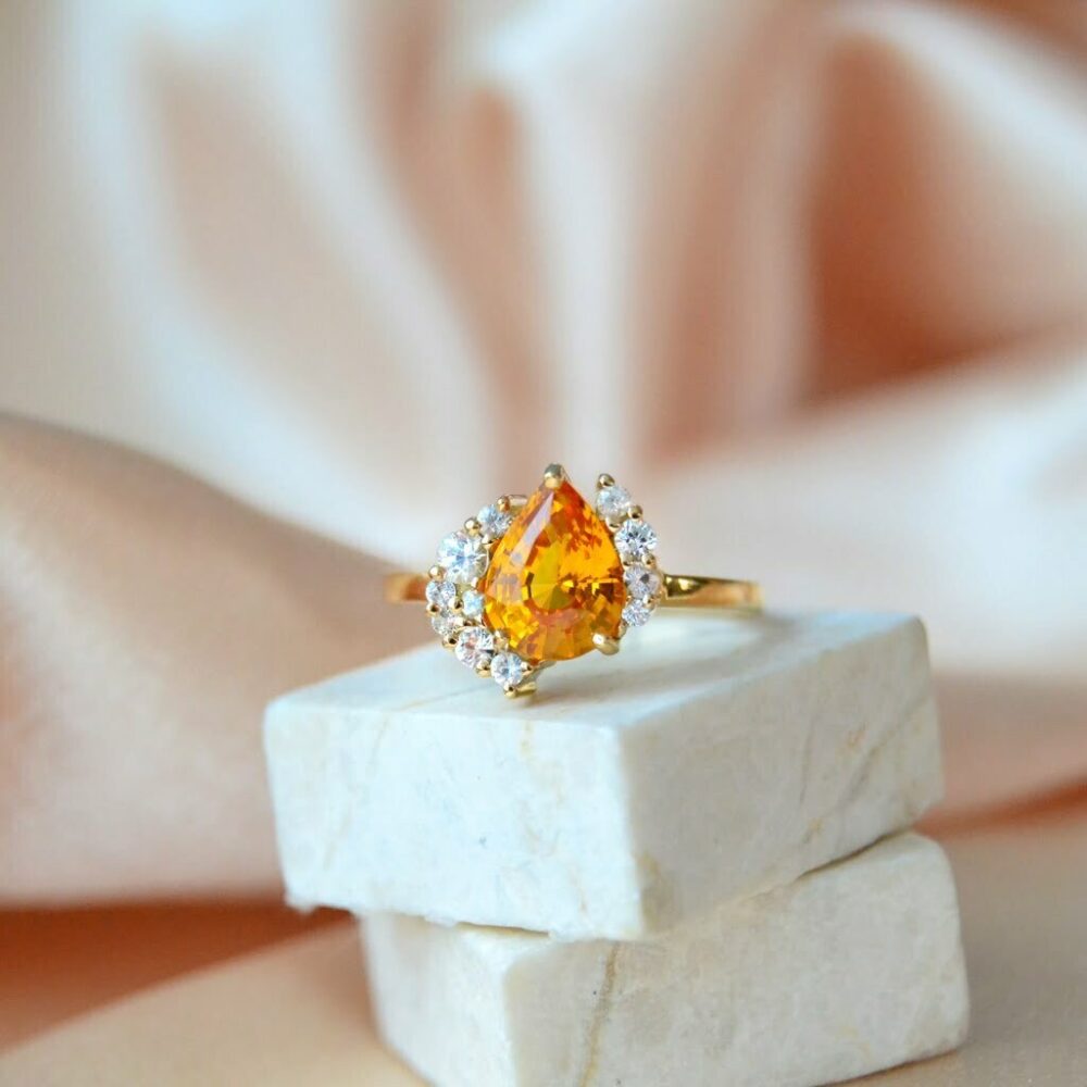 Orange sapphire asymmetric halo ring