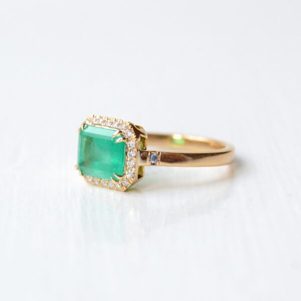 east west ring with emerald and diamonds set in 18K yellow gold.
