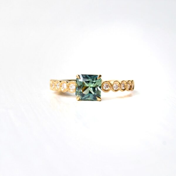 radiant cut green sapphire set with diamonds in 18K yellow gold.