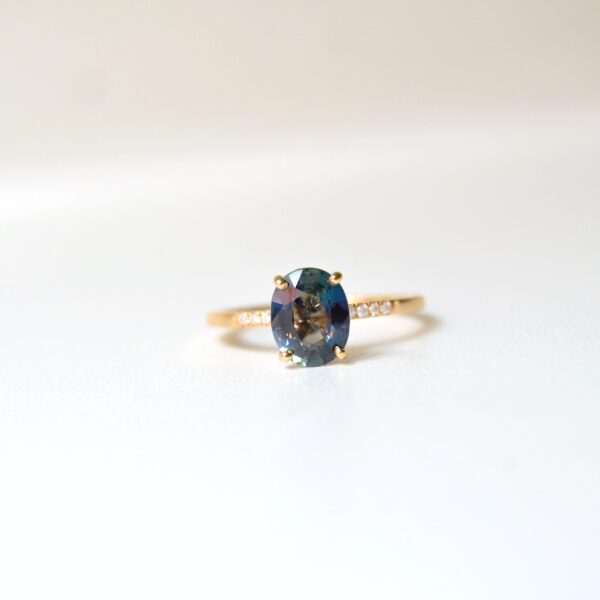 Oval teal sapphire ring with loads of sparkly diamonds set in 18K yellow gold.