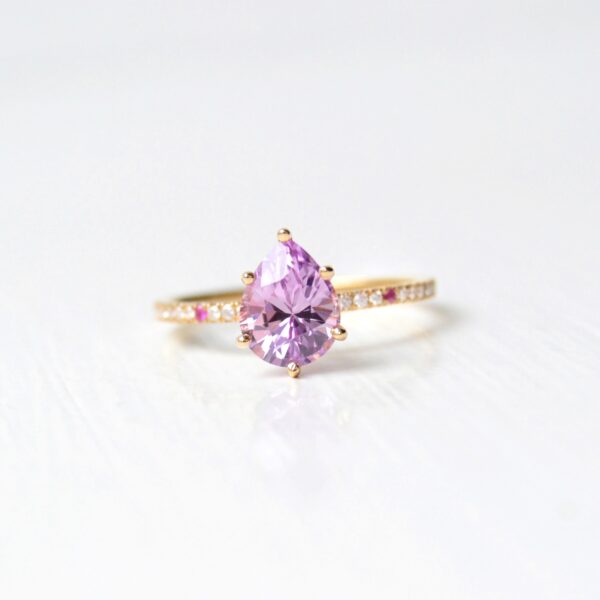 Pear shaped pink sapphire ring with diamonds set in 18K yellow gold.