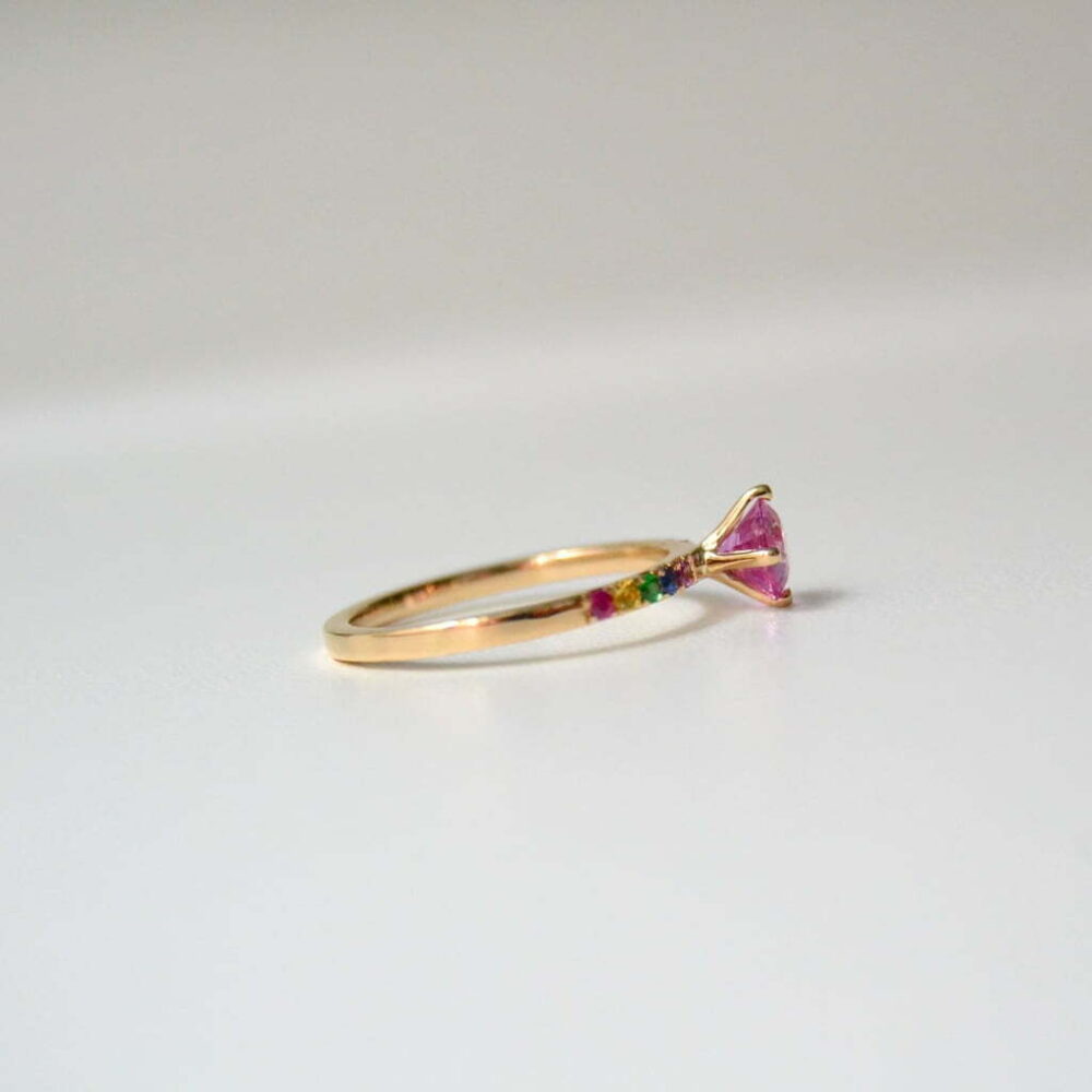 Pink sapphire solitaire ring with rainbow sapphires in the gold band